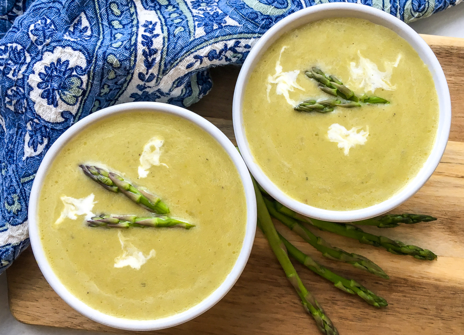 2 bowls of pressure cooker low histamine creamy asparagus soup with garnish of asparagus tops and cream