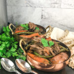 pot roast with sweet potatoes in large serving bowl topped with parsley garnish